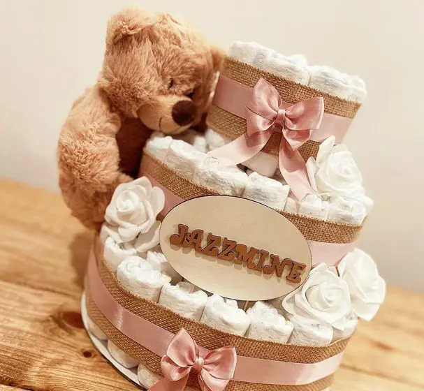 A teddy bear sitting on top of a diaper cake.
